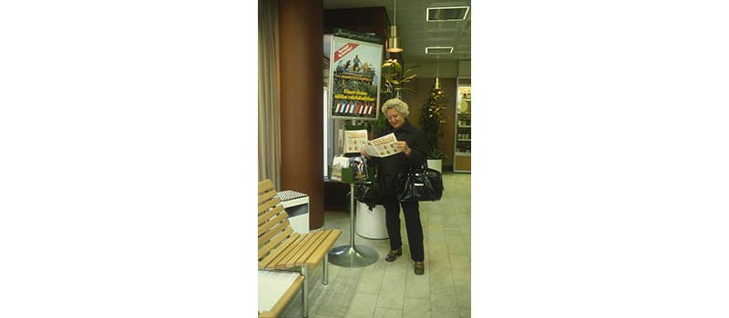 Butiksmiljö, äldre dam läser prislista Tidpunkt: 1983; Deponent: Systembolaget / Systembolaget AB; Motiv-ID: DA-2015-089573-SYS000852